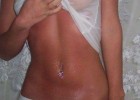 Tanned lady with hurt belly by the piercing infection