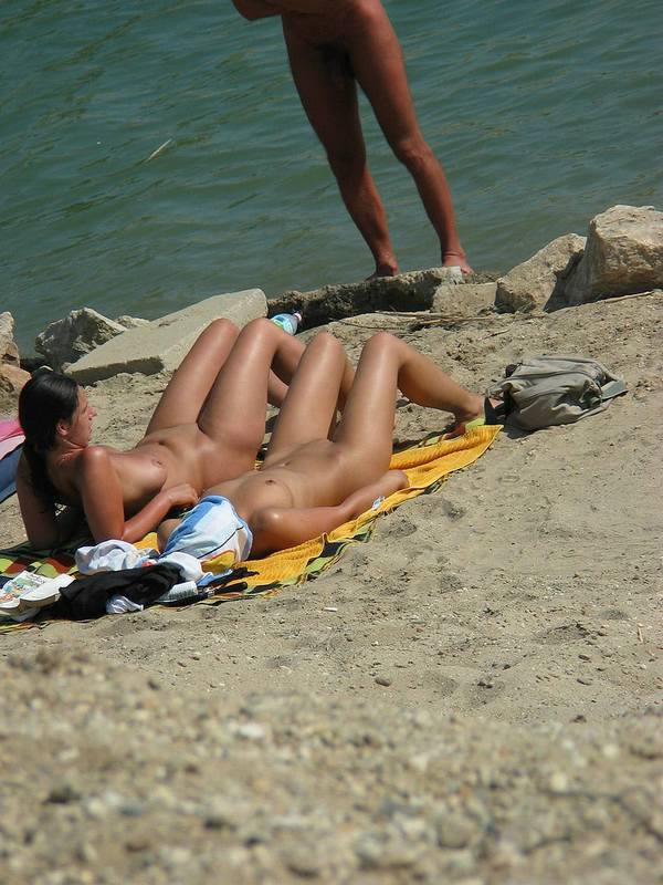 Oiled up chicks lying naked in the sun with their legs spread over the hot beach