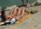 Oiled up chicks lying naked in the sun with their legs spread over the hot beach